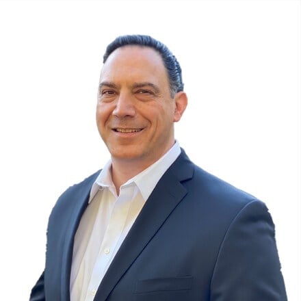 Professional headshot of a middle-aged man with dark hair wearing a navy blazer and white dress shirt against a white background